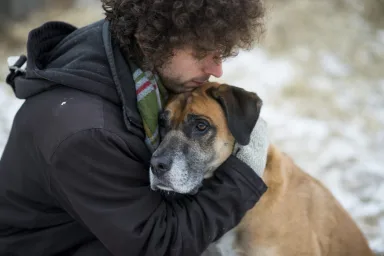 young man sadly hugging dog to say goodbye