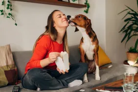 dog licking woman's face while eating take-out